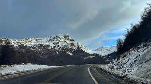 Road amidst snowcapped mountains against sky