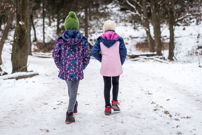 Rear view of women walking on snow covered land