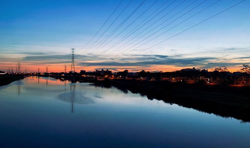 Reflection of electricity pylon against sky during sunset