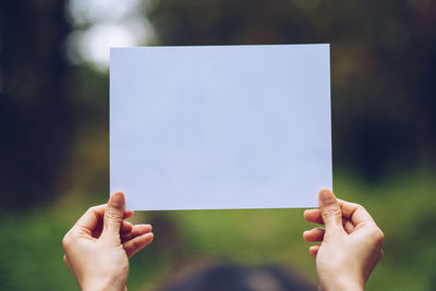 Midsection of person holding paper against blurred background