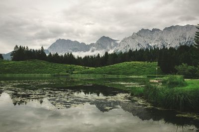 Scenic view of lake and mountains against cloudy sky