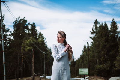 Woman standing against plants and trees against sky