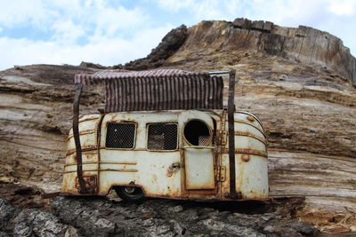 Old rusty metal on rock against sky