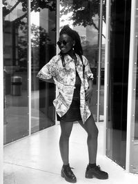 Full length portrait of young woman standing against building