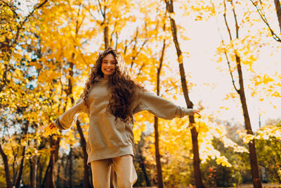 Young woman standing against trees