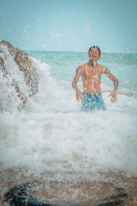 Full length of man splashing water at beach