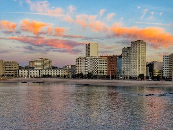 City at waterfront against cloudy sky