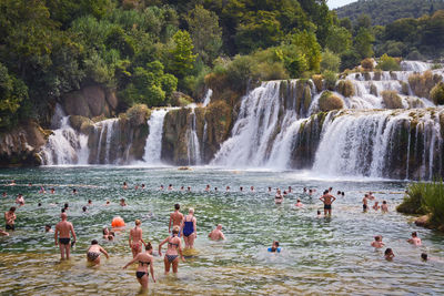 People enjoying in river against waterfall