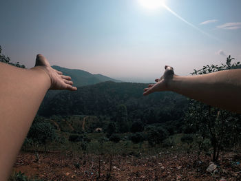 Midsection of man with arms raised against sky