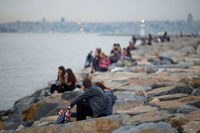 Couple sitting on groynes by sea