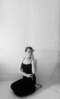 Young woman sitting against white background