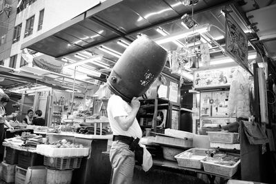 Man with face in plastic barrel at market stall