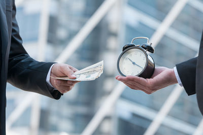 Close-up of hand holding clock against blurred background