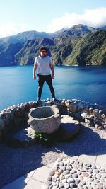 Man standing at observation point by lake and mountains against sky