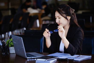 Side view of young woman using laptop on table