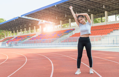 Full length of beautiful young woman standing at running track