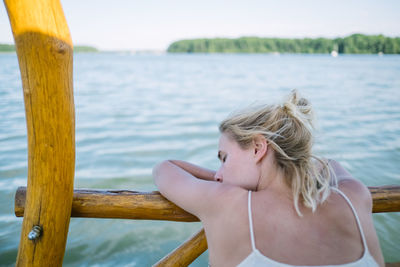 Rear view of woman relaxing on railing against sea
