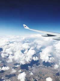 Airplane flying over cloudscape against blue sky