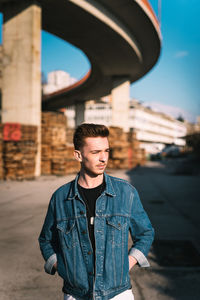 Young man looking away while standing on road