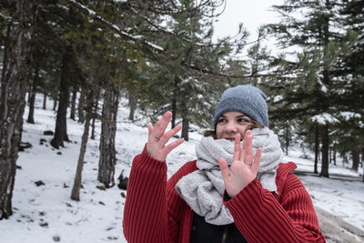 Portrait of young woman standing on snow covered field