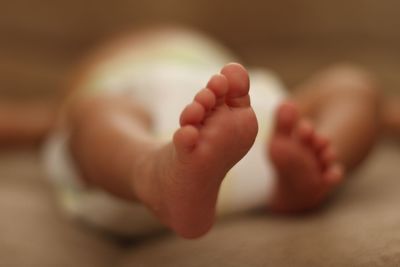 Low section of baby lying on bed