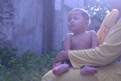 A child is sunbathing in the morning accompanied by his mother