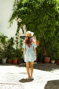 Rear view of young woman wearing hat while standing on footpath
