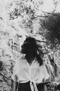 Portrait of young woman standing against waterfall