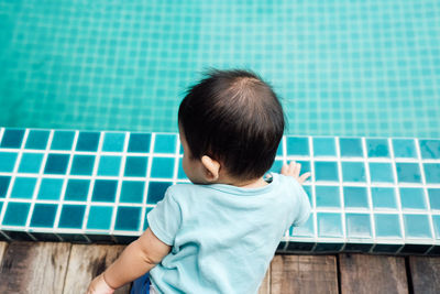 Rear view of baby girl sitting by swimming pool