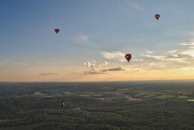 Hot air balloons flying over landscape against sky