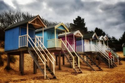 Built structure on beach by houses against sky