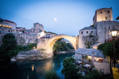 Arch bridge over river against buildings