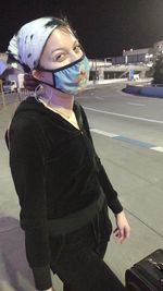 Portrait of smiling girl standing on road at night