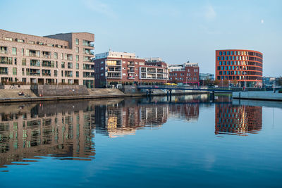 Reflection of buildings in river against blue sky