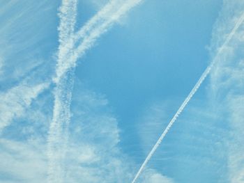 Low angle view of vapor trails in blue sky