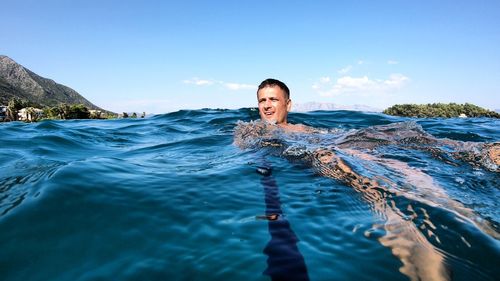 Man swimming in sea against sky