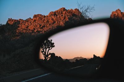 Clear sky reflecting on side-view mirror at sunset