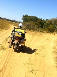 Man riding motorcycle on desert against clear sky