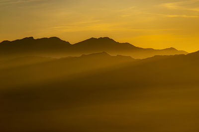 Scenic view of silhouette mountains against sky during sunset