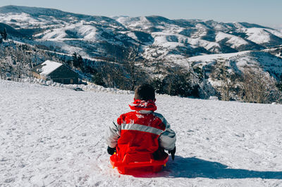 Rear view of person on snowcapped mountain