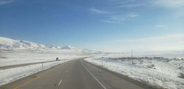 Road by snowcapped mountain against sky