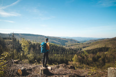 Rear view of man walking on mountain against sky