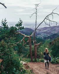 Rear view of woman walking on street against sky