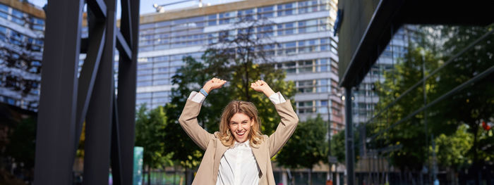 Portrait of young woman standing by railing