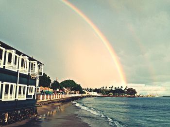 Rainbow over sea against cloudy sky