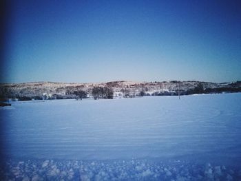 Scenic view of frozen landscape against clear blue sky