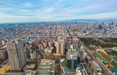 High angle view of city buildings against cloudy sky