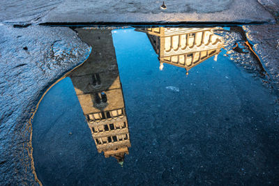 Reflection of building in puddle on street
