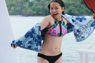 Portrait of cheerful young woman in bikini on boat at sea