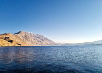 Scenic view of sea and mountains against clear blue sky